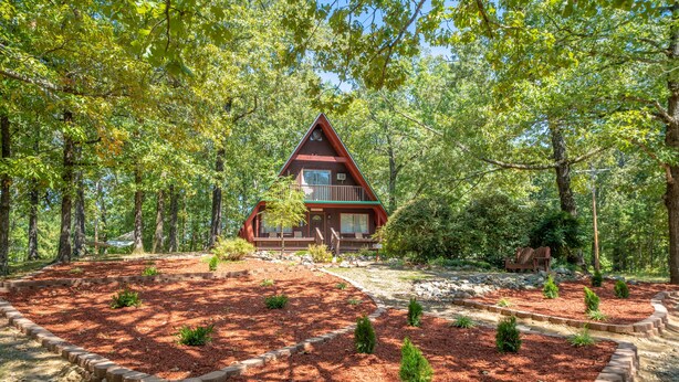 A cabin surrounded by a forest with a well-maintained garden and a stone pathway leading to the entrance. - Woodsy cabin perfect for a couple or a group! (Hot Springs)