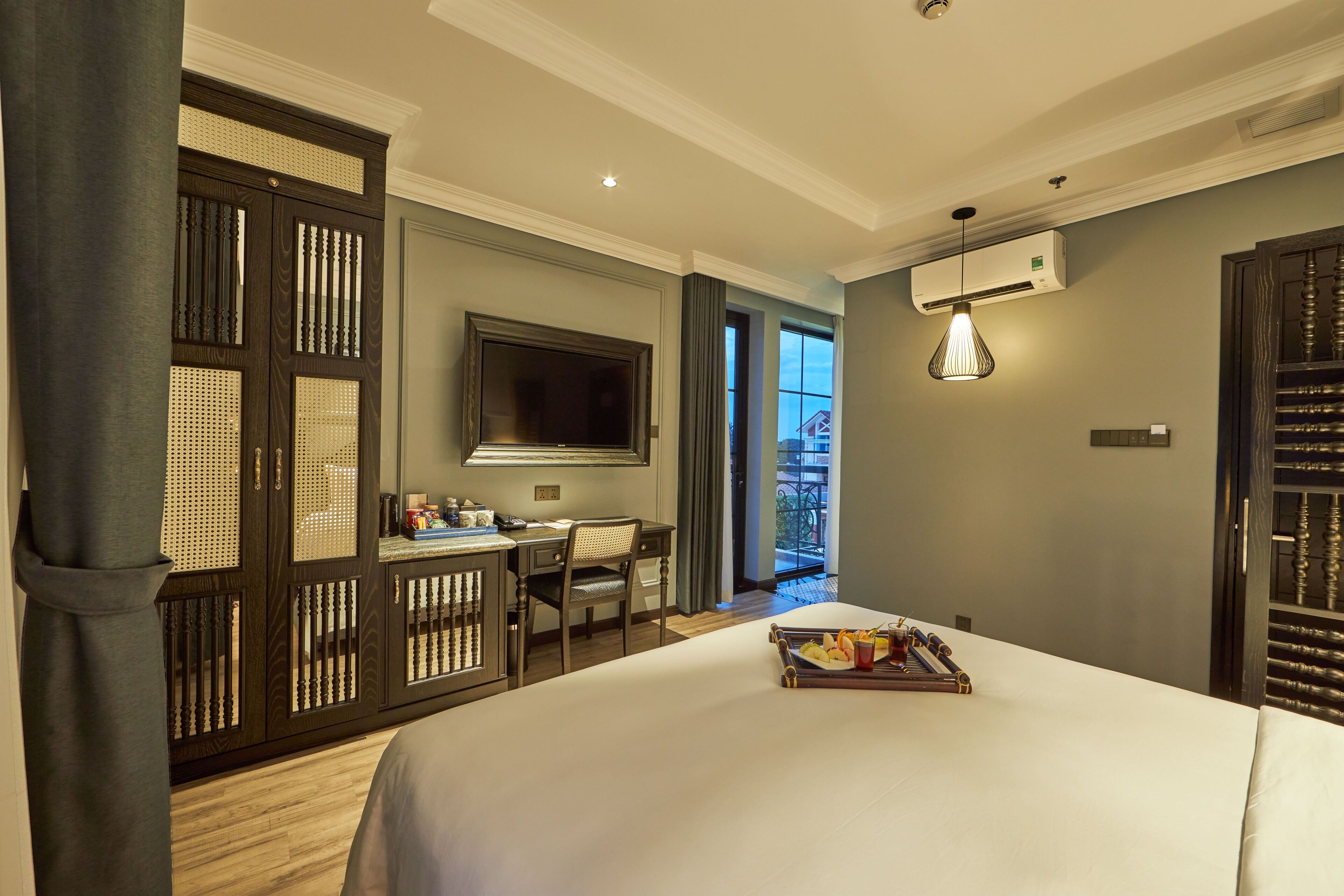 Ein Hotelzimmer mit Bett, Schreibtisch, Stuhl, Fernseher und Balkonblick.