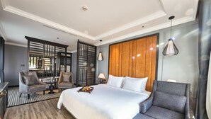 A hotel room with a large bed, two armchairs, a wooden headboard, and a decorative partition. - Hotel DMelin (Ho Chi Minh City)