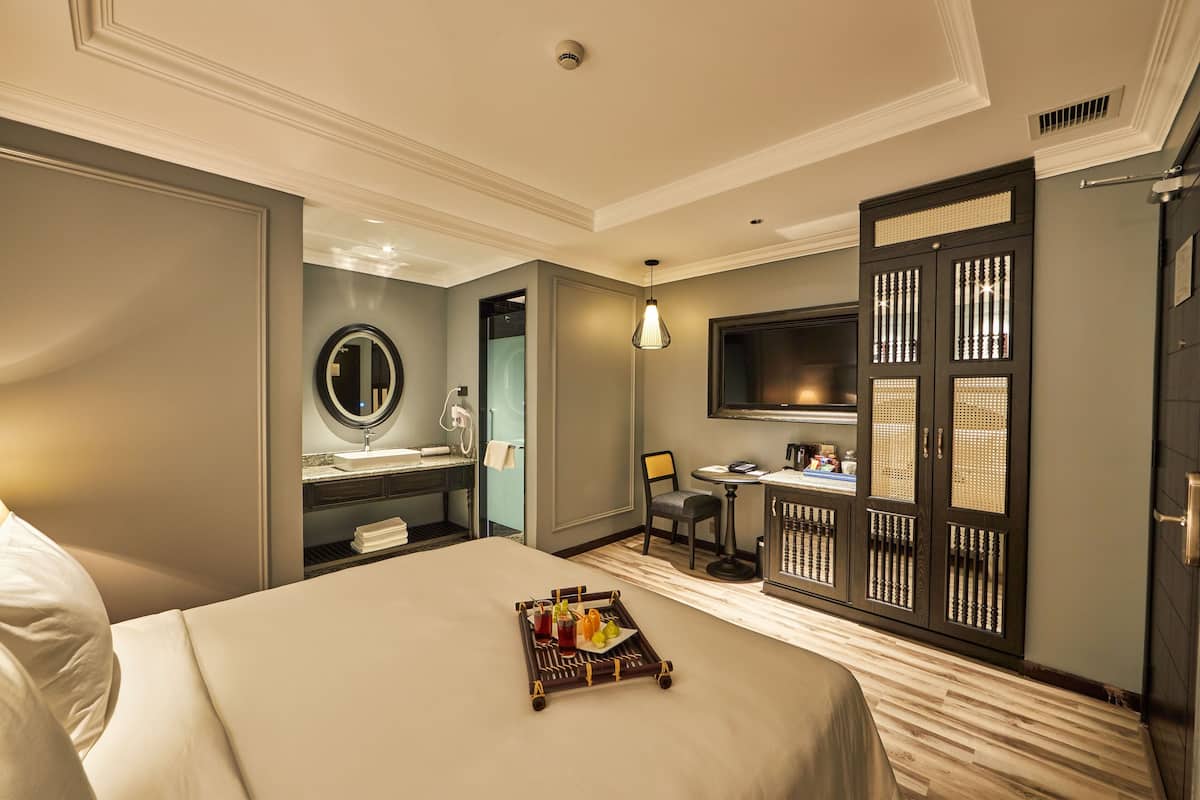 A hotel room with a bed, a desk, a TV, a wardrobe, and a bathroom.