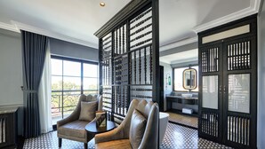 A room with a patterned floor, a seating area with two chairs, a small table, and a large window with curtains. - Hotel DMelin (Ho Chi Minh City)