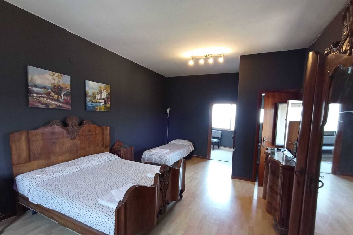 A bedroom with two beds, dark walls, and a wooden floor.