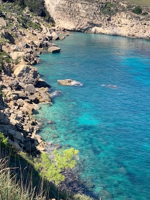 A coastal landscape with clear turquoise water, rocky terrain, and sparse vegetation. - Sbarcatore dei Turchi - Dimore (Augusta)
