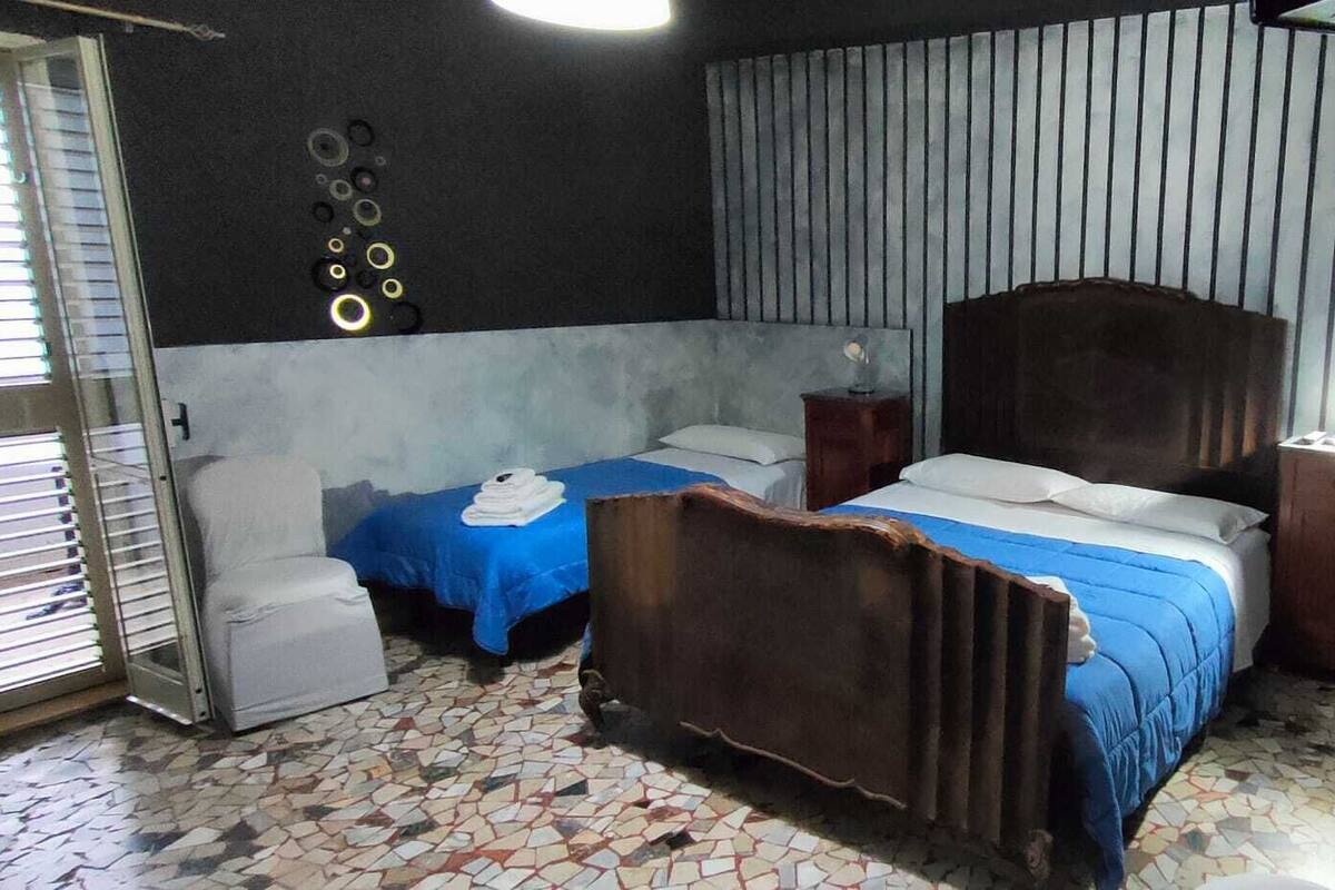 A room with two beds, a small desk, a chair, a tiled floor, and a wall with circular decorations.