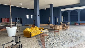 A spacious lobby with a yellow sofa, a large white planter, and a patterned floor.