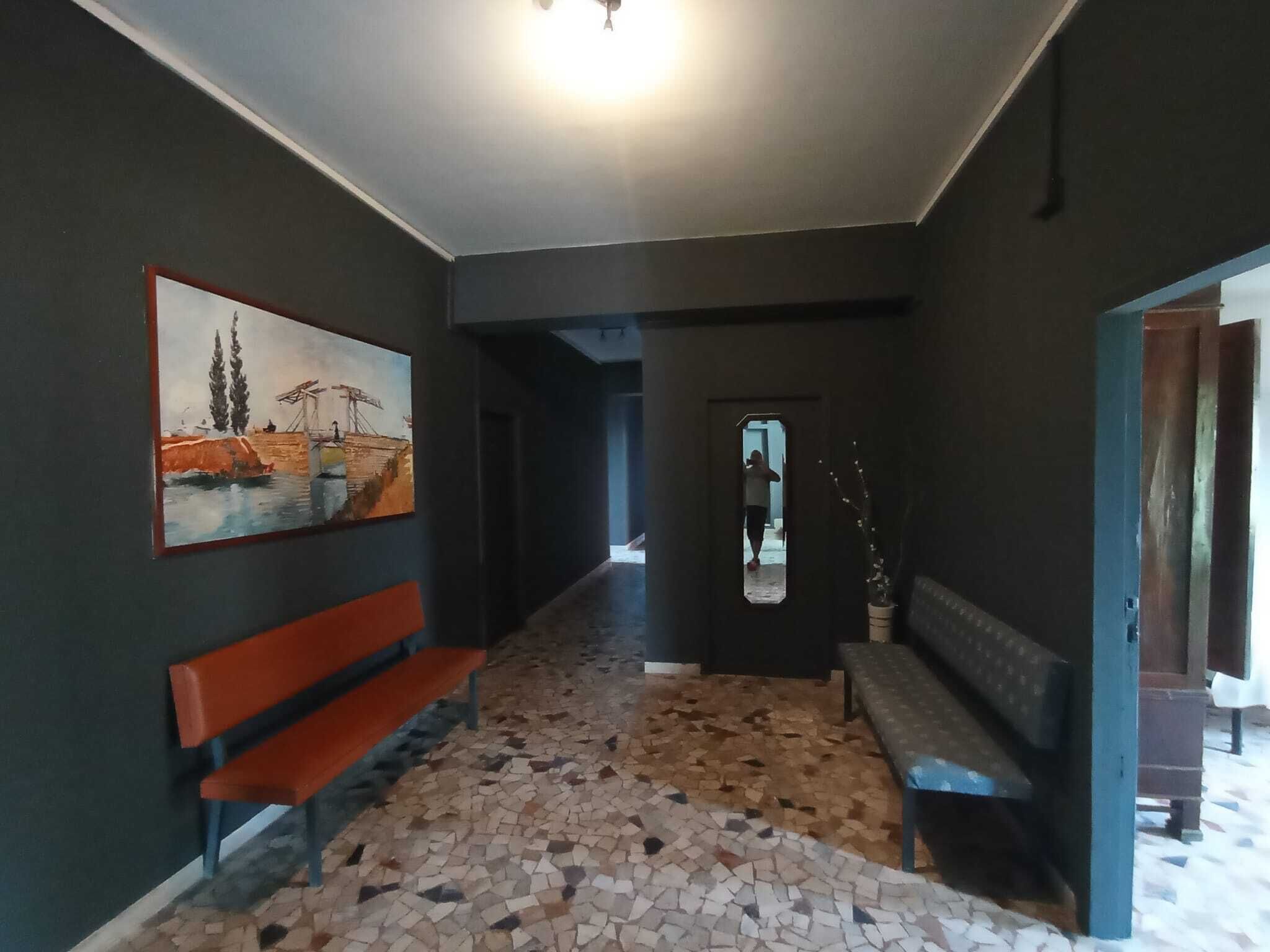 Un pasillo con un banco, un cuadro en la pared y un suelo de baldosas.