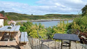 Montaje para picnic con una mesa y sillas con vista a un lago, rodeado de follaje y colinas.