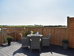 A wooden deck with wicker furniture and potted plants. - Y Bwthyn at Tyddyn Obry (Ty Croes)