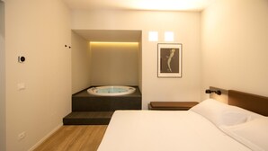 Een hotelkamer met een bed, een zithoekje, een aan de muur hangend schilderij en een bad.