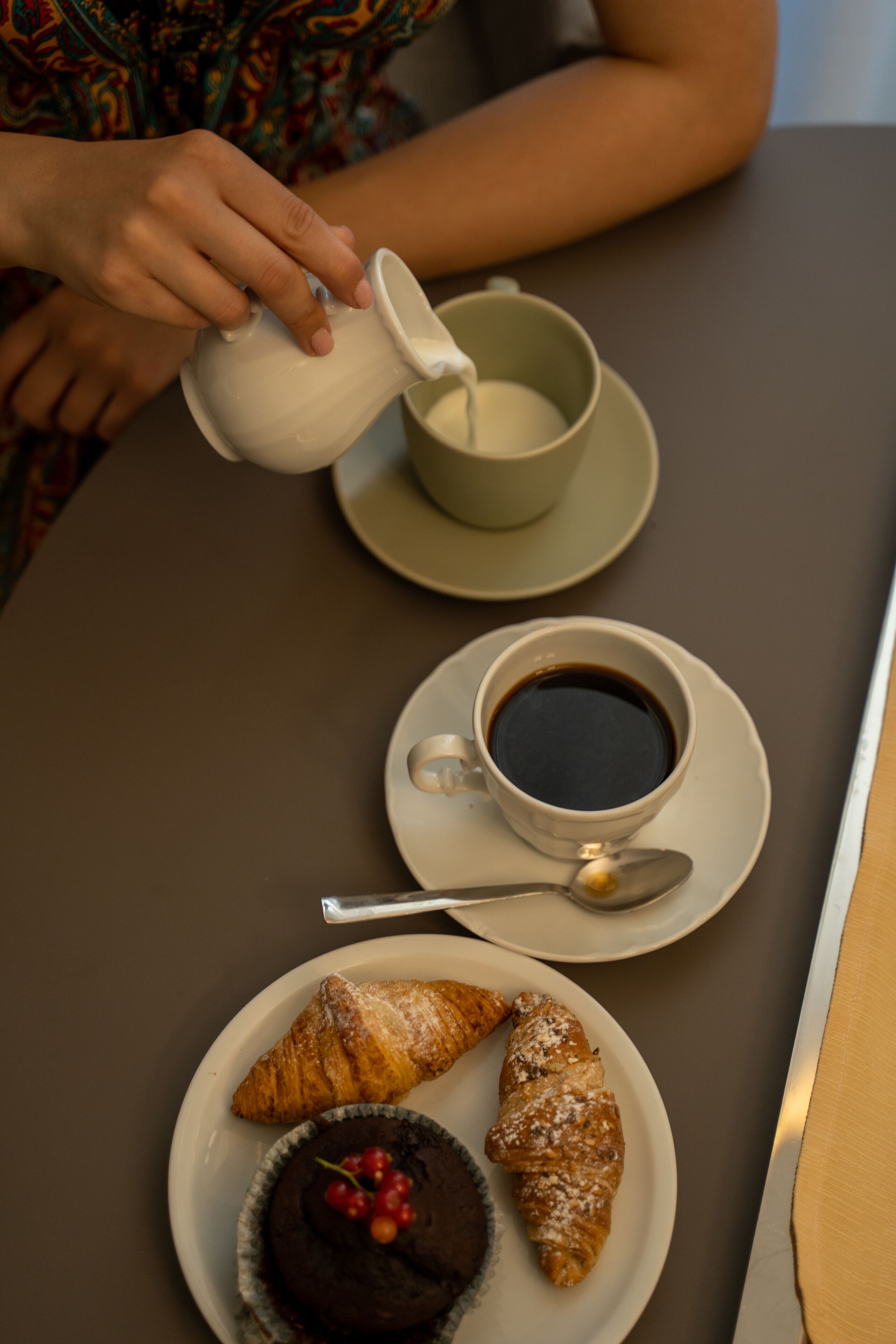 Una mesa con una taza de café, un pastel y un postre.