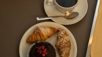 Una mesa con una taza de café, un pastel y un postre.