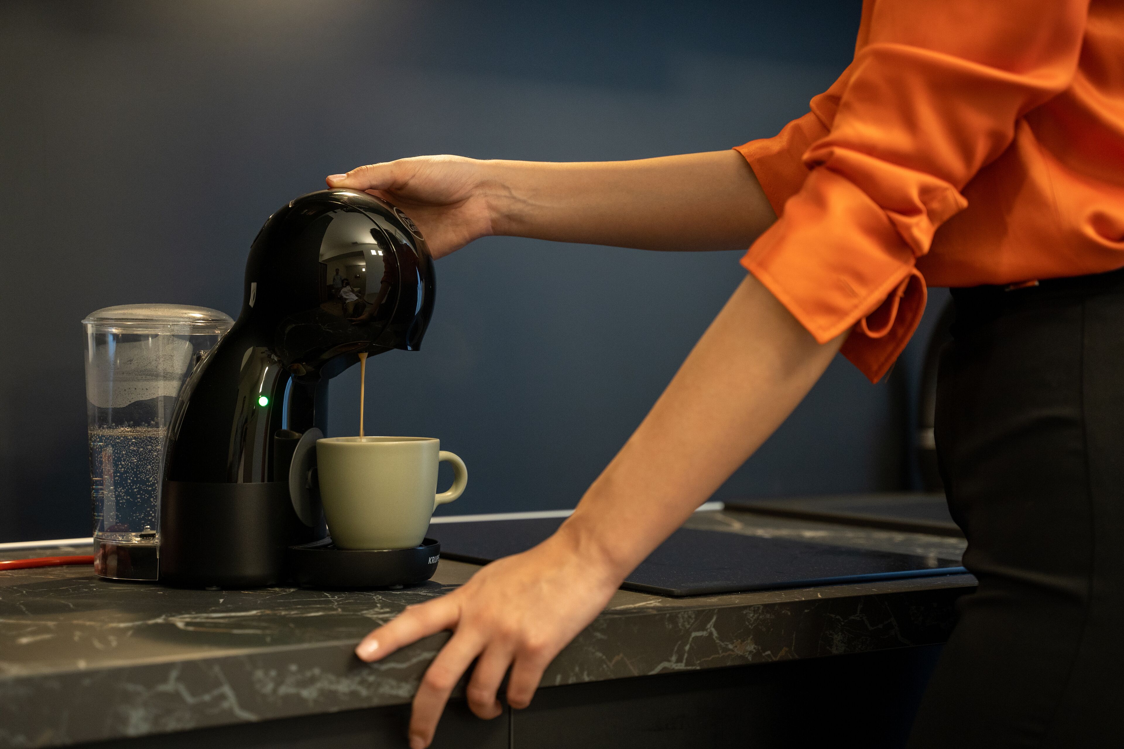 Une personne verse du café d’une cafetière noire dans une tasse.