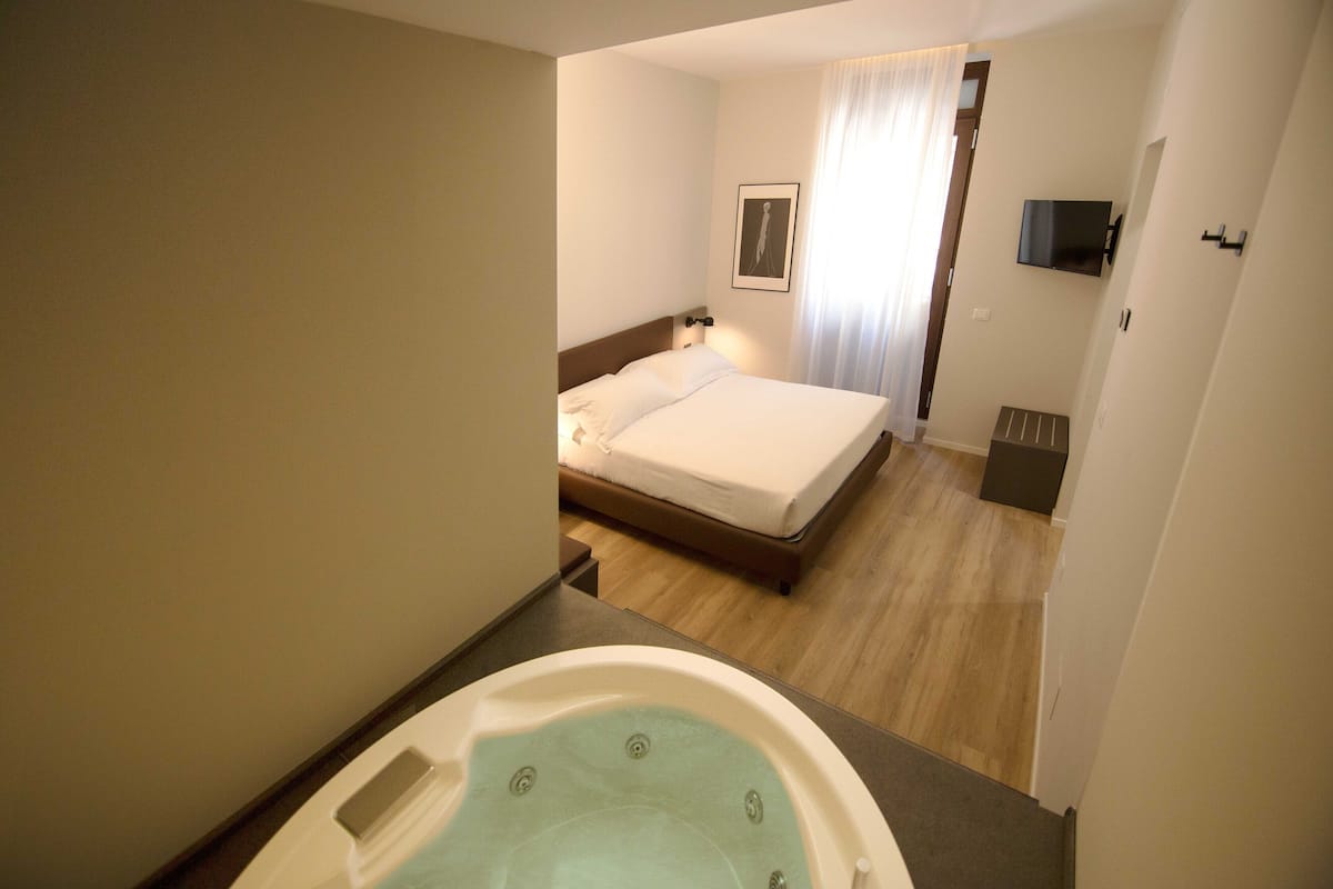 Une chambre d’hôtel avec un lit, un téléviseur fixé au mur et une salle de bain avec une baignoire.