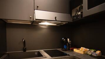 A modern kitchen with dark cabinetry, a stainless steel sink, and a built-in oven.
