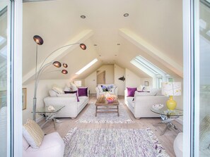 Ein großzügiger Lofts mit hohen Decken, Oberlichtern und einer zentralen Sitzecke mit Sofas und einem Couchtisch.