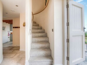 A staircase leading to a room with a white door, a light switch, and a radiator in the background.