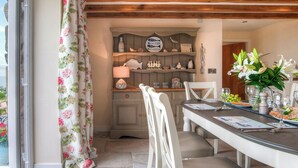 Un coin repas avec une table dressée pour deux personnes, un plafond en bois et une vue par la fenêtre.