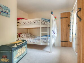 A bunk bed room with a wooden door, a radiator, and a small chest of drawers.