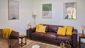 A living room with a brown leather sofa, a brown armchair, a rug, and a dog. - 1 bedroom accommodation in Clynnog Fawr (Clynnog Fawr)