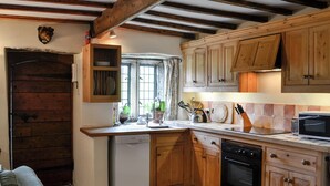 A rustic kitchen with wooden cabinets, a dishwasher, and a large window.
