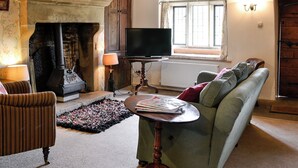 A cozy living room with a fireplace, a television, a sofa, and a patterned rug.
