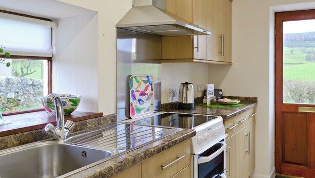 A modern kitchen with a stainless steel sink, a built-in oven, and a window with a view of the countryside. - Beuchan Cottage Keir Mill (Keir Mill, Thornhill)