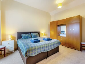 A bedroom with a bed, nightstands, a wardrobe, and a mirror.
