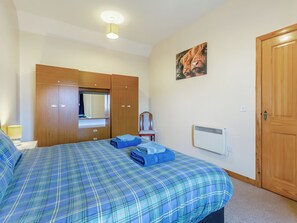 A bedroom with a bed, a wardrobe, a radiator, and a painting on the wall.