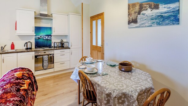 Una cocina moderna con armarios blancos, una estufa y un comedor con una mesa dispuesta para dos.
