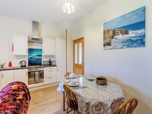 A modern kitchen with white cabinets, a stove, and a dining area with a table set for two.