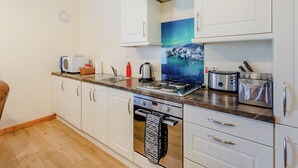 Una cocina moderna con armarios blancos, una estufa de acero inoxidable y un microondas.