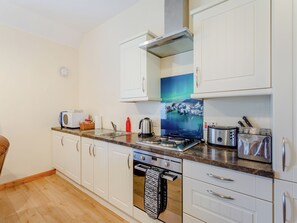 A modern kitchen with white cabinets, a stainless steel stove, and a microwave.