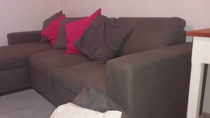 A brown sofa with red and gray cushions in a room with a white wall and a wooden table. - Countryside italian villa, close to the sea (Jerzu)