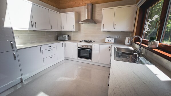 A modern kitchen with white cabinets, a built-in oven, a microwave, a gas stove, and a stainless steel sink.