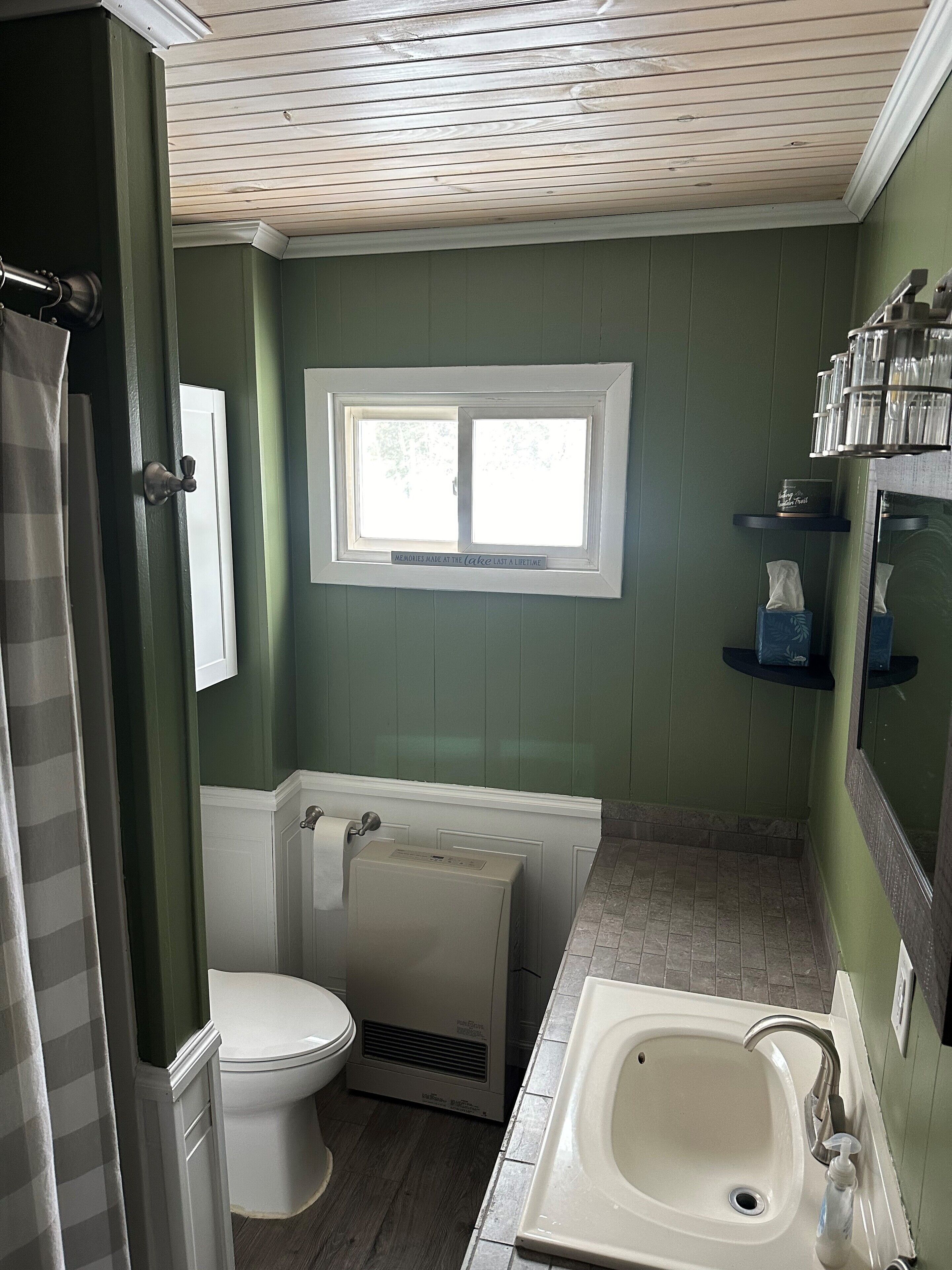 A bathroom with a toilet, a sink, a window, and a shower curtain.