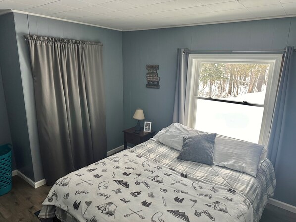 A bedroom with a bed, a nightstand, a window with curtains, and a wall sign. - Newly Renovated, perfectly located and fully equiped. (Portage Lake)