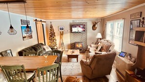 A cozy living room with a fireplace, wooden furniture, and a dog lying on the floor. - Newly Renovated, perfectly located and fully equiped. (Portage Lake)