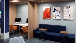Un espacio de oficina moderno con un escritorio, dos sillas, un sofá azul y tres cuadros en la pared.