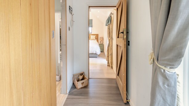 Ein Flur mit einem Holzschrank, einer kleinen Holzkiste und einem Schlafzimmer mit Bett und Nachttisch.