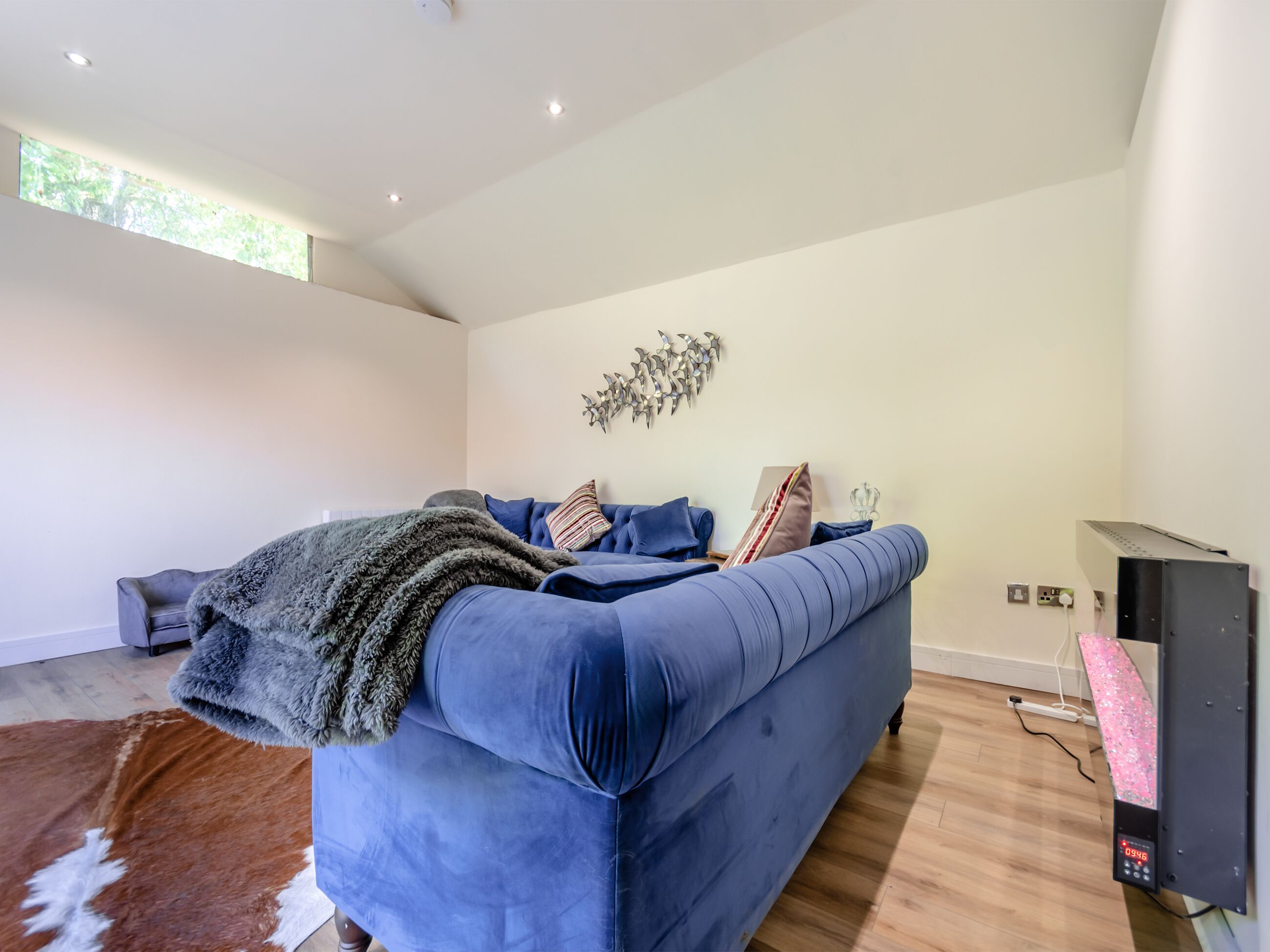 Una sala de estar moderna con un sofá azul, un adorno de pared y suelo de madera.