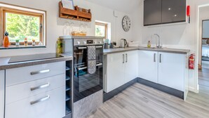 Eine moderne Küche mit weißen Schränken, einem eingebauten Backofen und einem großen Fenster.