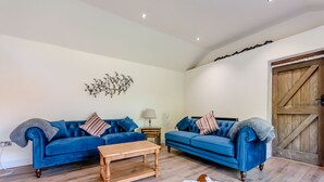 Ein Wohnzimmer mit zwei blauen Sofas, einem Holztisch, einem Cowhide-Teppich und einer Wanddekoration.