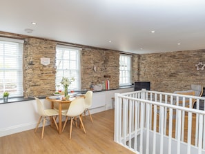 A dining area with a stone wall, wooden flooring, and a white railing.