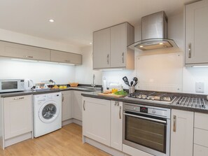 A modern kitchen with a built-in washing machine, an oven, and a microwave.