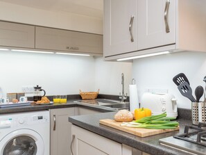 A modern kitchen with a washing machine, toaster, and various kitchen utensils on the counter.