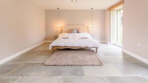 Een slaapkamer met een bed, twee nachtkastjes, een vloerkleed en een groot raam.