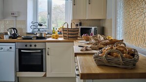 Een keuken met een vaatwasser, oven, magnetron en een houten aanrecht met brood en een mand.