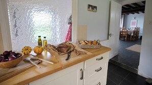 Een keukenblad met een houten snijplank, een brood, een mes en een kom rode uien.