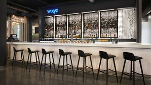 A bar area with a neon sign, a bar counter, and multiple stools. - Aloft by Marriott Atlanta Perimeter Center (Atlanta)