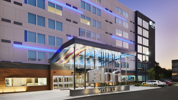 A modern hotel with a glass facade, multiple floors, and a prominent entrance. - Aloft by Marriott Atlanta Perimeter Center (Atlanta)